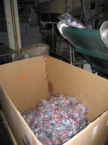 .<br />Пазлы в пакетах собираются в специальные емкости, откуда перевозятся в другой цех, где снова попадают на конвейер.